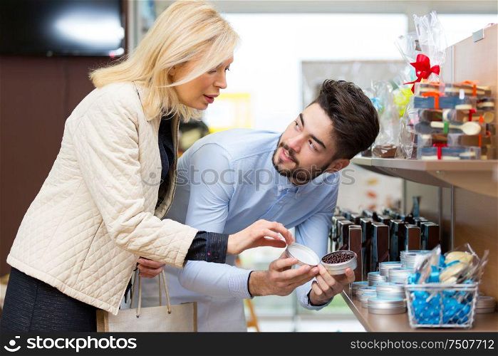 young man chooses chocolates in store