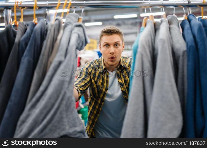 Young man choosing bathrobe in bed linen store. Male person buying home goods in market, guy in bedding shop. Young man choosing bathrobe in bed linen store