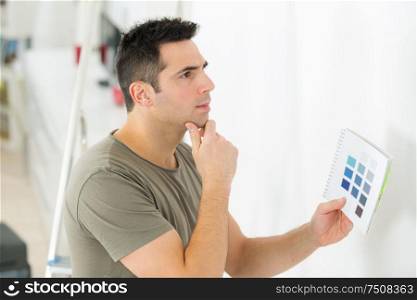 young man choosing color for walls to paint