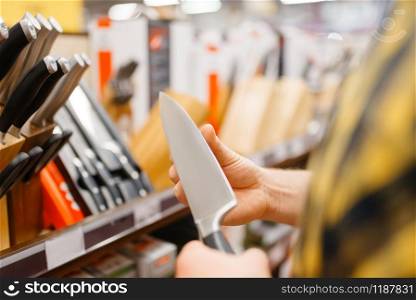 Young man choosing kitchen knife in houseware store. Male person buying home goods in market, guy in kitchenware supply shop. Young man choosing kitchen knife, houseware store