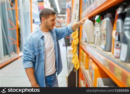Young man choosing repair materials in hardware store. Customer look at the goods in diy shop
