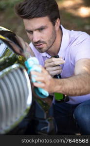 young man cleaning carefully hi car