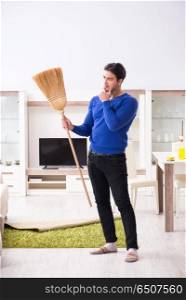 Young man cleaning floor with broom