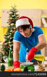 Young man cleaning kitchen after Christmas party 