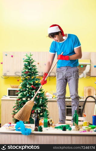 Young man cleaning kitchen after Christmas party 