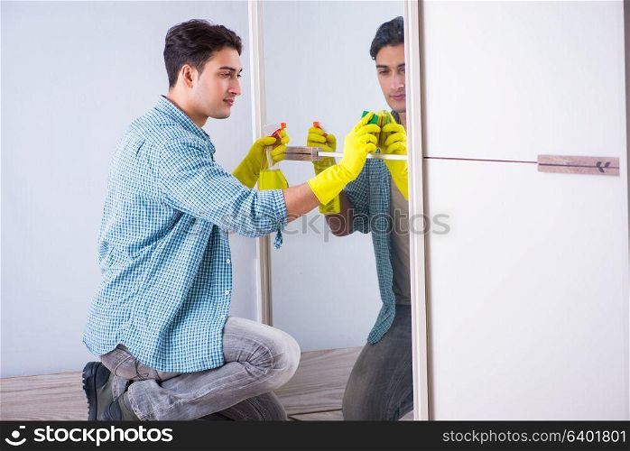 Young man cleaning mirror at home hotel