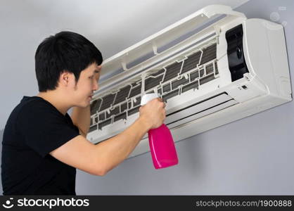 young man cleaning the air conditioner indoors at home