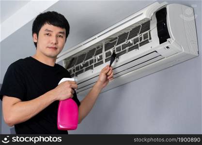 young man cleaning the air conditioner indoors at home