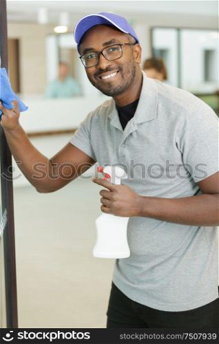 young man cleaning window in office