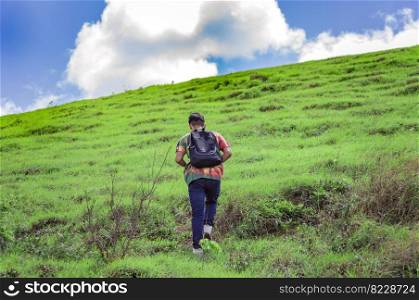 Young man climbing a hill with blue sky , back traveler climbing a hill, back guy hiking