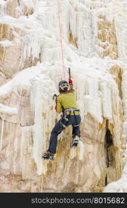 Young man climbing the ice using ice axe