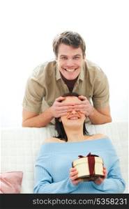 Young man closing eye to girlfriend to present gift