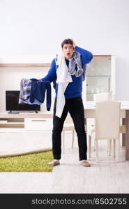 Young man collecting dirty clothing for laundry