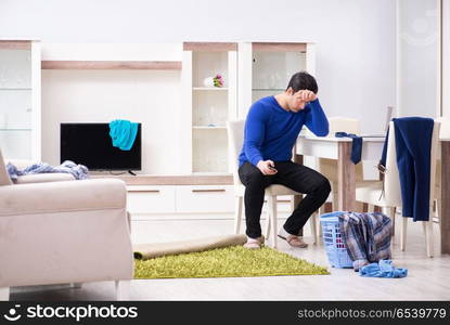 Young man collecting dirty clothing for laundry