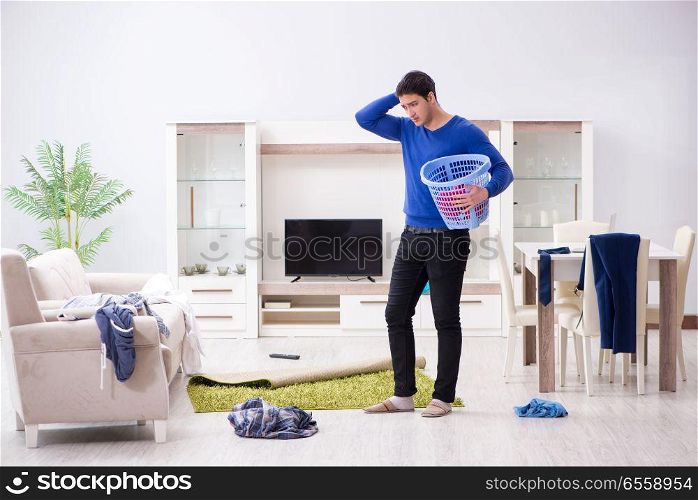 Young man collecting dirty clothing for laundry