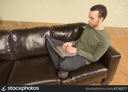 Young Man Computing on Couch