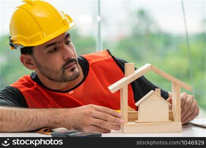 Young man construction worker or engineer working at desk with designer equipment to make interior design at workplace. Real estate business and civil engineering concept.