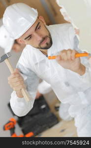 young man contactor with a chisel and hammer