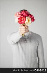 young man covering his face with bouquet of flowers.