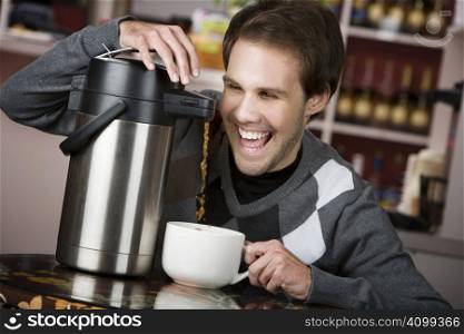 Young man crazily pouring coffee from a thermos in a cafe