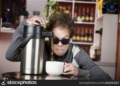 Young man crazily pouring coffee from a thermos in a cafe
