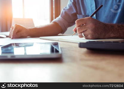 Young man crew works with a new startup program in a modern attic. Pencil handshake laptop analyzes wide horizontal plan in the afternoon.