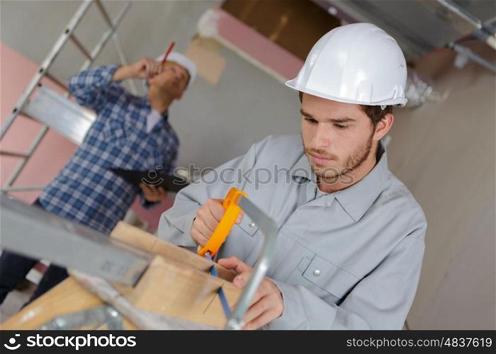young man cutting a board with a hand saw