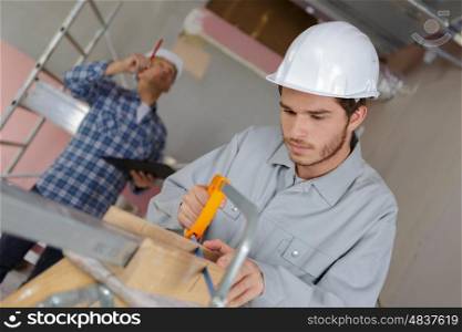 young man cutting a board with a hand saw