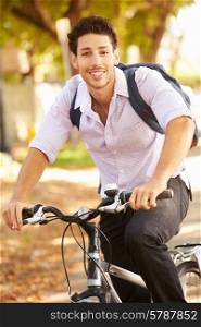 Young Man Cycling Along Street To Work