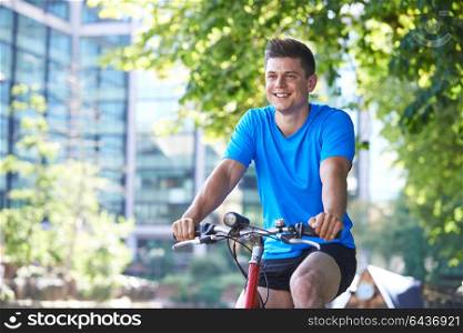 Young Man Cycling Next To River In Urban Setting