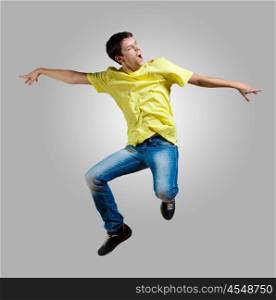 Young man dancing and jumping. Modern slim hip-hop style man jumping dancing on a grey background