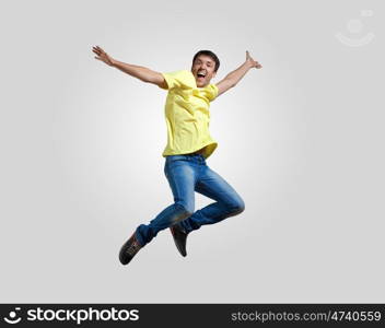 Young man dancing and jumping. Modern slim hip-hop style man jumping dancing on a grey background