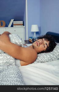 Young man deep asleep in bed at home