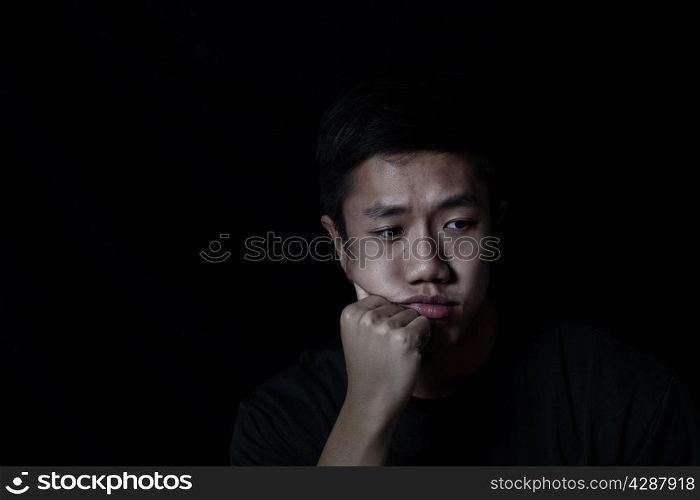 Young man depressed on black background
