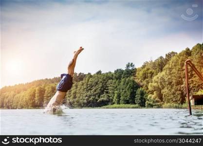 Young man diving into a lake. Careless and risky water jump. Summer vacation dangerous outdoor activity. Side view.. Young man diving into a lake.