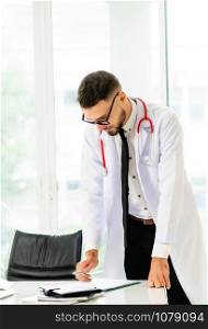 Young man doctor working at office desk in hospital. Medical and healthcare concept.