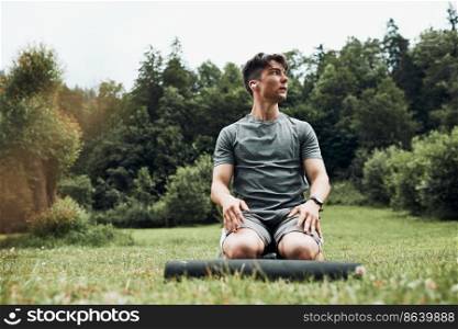 Young man doing exercises outside on grass during his calisthenics workout. Teenager training outdoors. Young man doing exercises outside on grass during his calisthenics workout