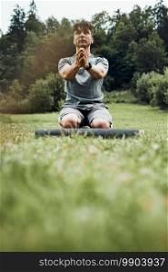 Young man doing exercises outside on grass during his calisthenics workout. Teenager training outdoors. Young man doing exercises outside on grass during his calisthenics workout