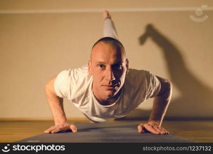 Young man doing one legged box push up yoga pose training at home