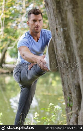 young man doing stretching against a tree in a park