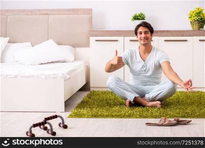 Young man doing yoga in bedroom 