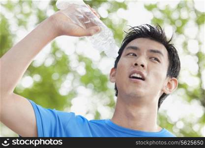 Young Man Drinking Bottled Water in Park