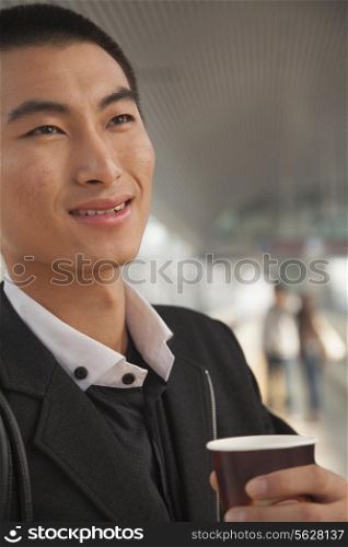 Young Man Drinking Coffee on Train Platform