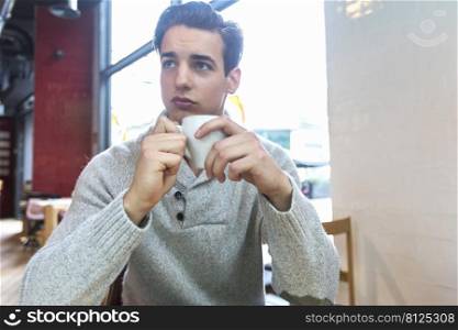 Young man drinking coffee while sitting in a coffee shop