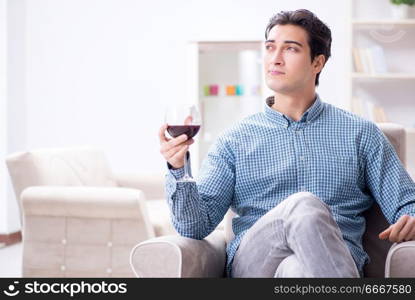 Young man drinking wine at home