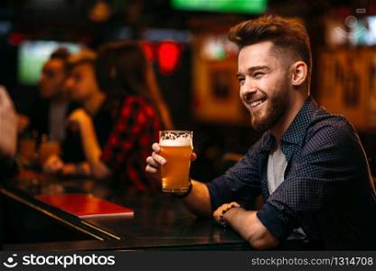 Young man drinks beer at the bar counter in a sport pub,. Man drinks beer at the bar counter in a sport pub