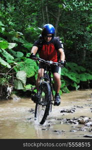 young man drive mountain bike over water river