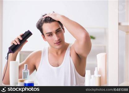 Young man drygin his hair in the morning