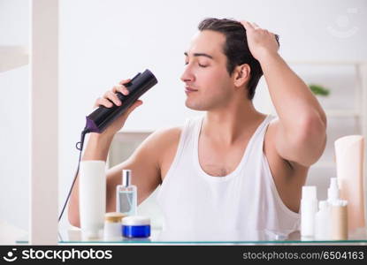 Young man drygin his hair in the morning