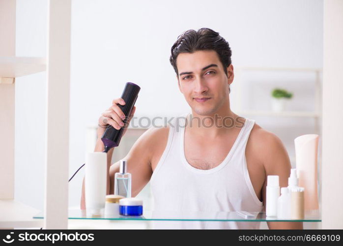 Young man drygin his hair in the morning